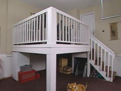 a dog laying on the floor in front of a white stair case with railings