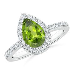 The earthy green brilliance of the peridot at the center is enhanced with a halo of glistening diamonds around it. Diamond accents cascade down the shoulders of the 14k white gold peridot ring for extra sparkle. The pear-shaped peridot ring is femininely alluring and stylish. Peridot Jewelry Rings, Peridot Engagement Rings, Pear Cut Ring, Peridot Jewelry, Gorgeous Engagement Ring, Ruby Engagement Ring, Ring With Diamond, Peridot Ring, Zircon Ring