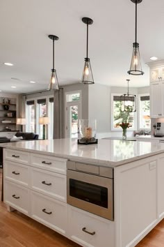 a large kitchen with an island in the middle and three lights hanging from the ceiling