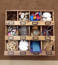 a wooden box filled with lots of crafting supplies on top of a carpeted floor