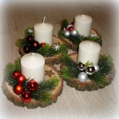 three white candles with christmas decorations on them sitting on top of a wooden slice in the middle of a table