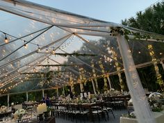 the inside of a large tent with tables and chairs set up for an outdoor wedding