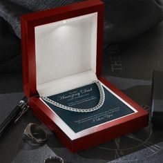 an open red box containing a necklace and some silverware on a black tablecloth