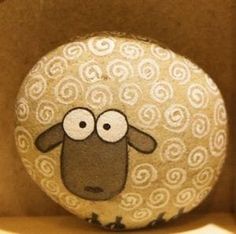 a sheep painted on top of a rock in a brown box with white swirls