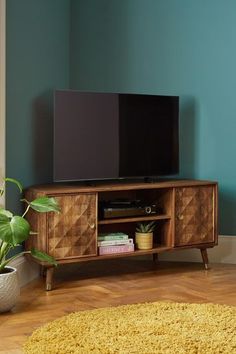 a flat screen tv sitting on top of a wooden entertainment center next to a potted plant