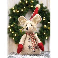 a stuffed mouse with a santa hat and candy cane in front of a christmas wreath