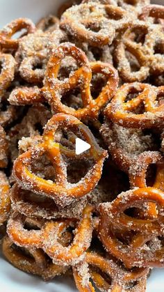 a white bowl filled with fried pretzels covered in powdered sugar