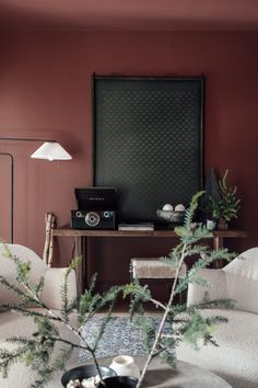 a living room filled with furniture and a plant on top of a coffee table in front of a painting