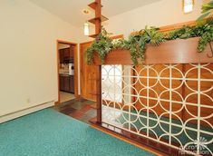 an empty living room with green plants on the wall and blue carpeted flooring