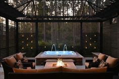 an outdoor hot tub and seating area with fire pit in the middle, surrounded by wood slats