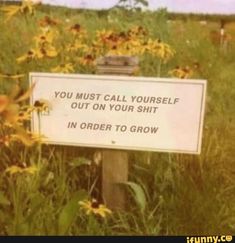 a sign that is in the grass near flowers