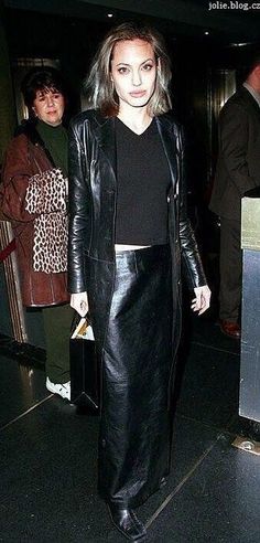 a woman in a black leather jacket and skirt