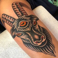 a goat head tattoo on the arm with red eyes and long horns is seen here