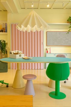 a dining room with pink and white striped walls, green chairs and a blue table