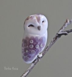 an owl figurine sitting on top of a tree branch in front of a gray background