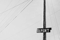 a street sign hanging from the side of a wooden pole in front of power lines