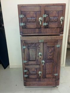 an old wooden cabinet with two doors and knobs on the front is sitting in a room