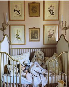 a baby in a crib with stuffed animals on the bed and pictures above it