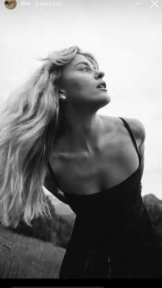 a black and white photo of a woman with her hair blowing in the wind looking up