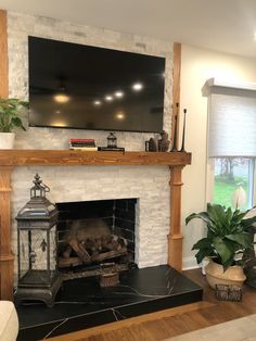 a fireplace with a flat screen tv above it and potted plants on the mantle