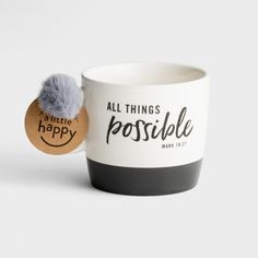 a coffee cup with a pom - pom in the middle and an all things happy sticker on it