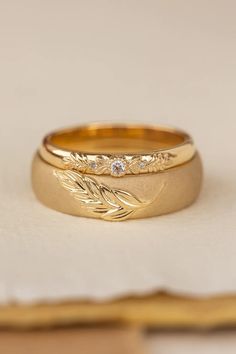 two gold wedding rings sitting on top of each other