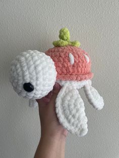 a hand holding up a crocheted stuffed animal with a hat on it's head