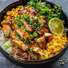 a bowl filled with rice and chicken next to corn on the cob, garnished with cilantro