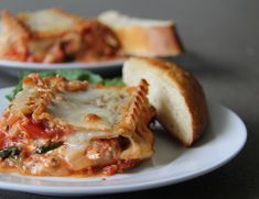 two white plates topped with lasagna and bread