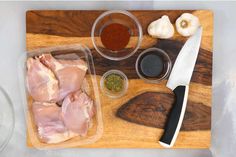 raw chicken on cutting board with spices and seasoning next to knife, pepper, garlic