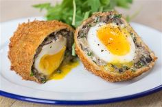 an egg in a bread roll on a white plate with green garnishes