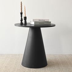 a black table with two candles on it and a book sitting on top of it