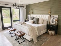 a bedroom with a large bed and two stools in front of the door that leads to an outside patio