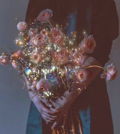 a person holding a bunch of flowers in their hands with sparkling lights on them and sparkles all over the bouquet