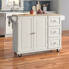 a white kitchen island with wooden top on wheels