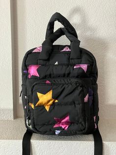 "Children's quilted black bagpack Gold, purple, blue and silver neon stars Soft Handle and adjustable back straps ZIpper closure 2 inside pockets big enought to hold an iphone and snack Key chain outside Condition is great Dimension - height 13\" length 10\" depth 5\" handle 6\"" Black Quilted School Bag, Black Quilted Standard Backpack, Black Quilted Backpack, Neon Stars, Quilted Cushion, Backpack Cute, Black Children, Childrens Backpacks, Black Quilt