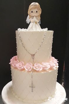 a wedding cake decorated with pink roses and a figurine