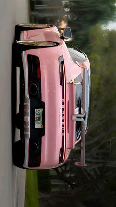 a pink sports car parked on the side of a road next to a white wall