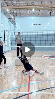 three people are playing volleyball in an indoor court with one person reaching for the ball