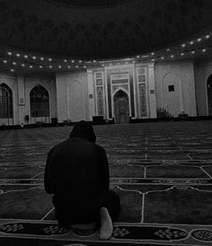 a man sitting on the floor in front of a large room with many windows and lights