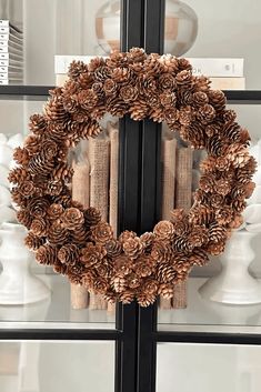 a wreath made out of pine cones is hanging on the front glass door with an advertizer in the background