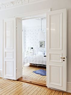 an open door in a white room with hardwood floors