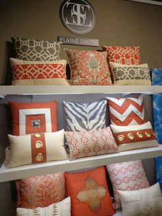 many pillows are on the shelves in a room that is decorated with orange, blue and white