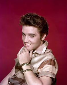 a young man with his hands on his chest posing for a photo in front of a red background