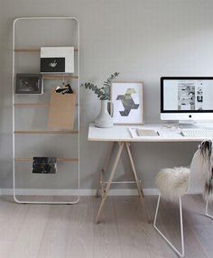 a white desk with a computer on top of it next to a bookshelf