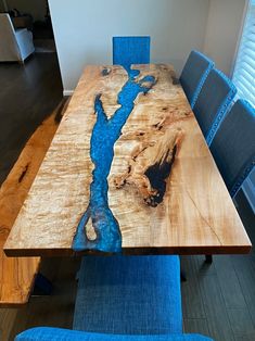 a wooden table with blue chairs around it and a river running through the center piece