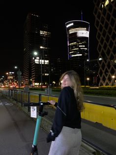 a woman is riding an electric scooter in the city at night, smiling