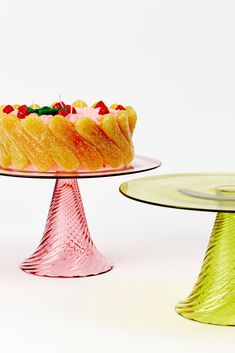 two cakes sitting on top of glass pedestals next to each other in front of a white background