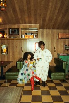 a man and woman sitting on a couch in a room with checkered flooring