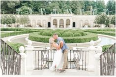 a man and woman kissing in front of a garden